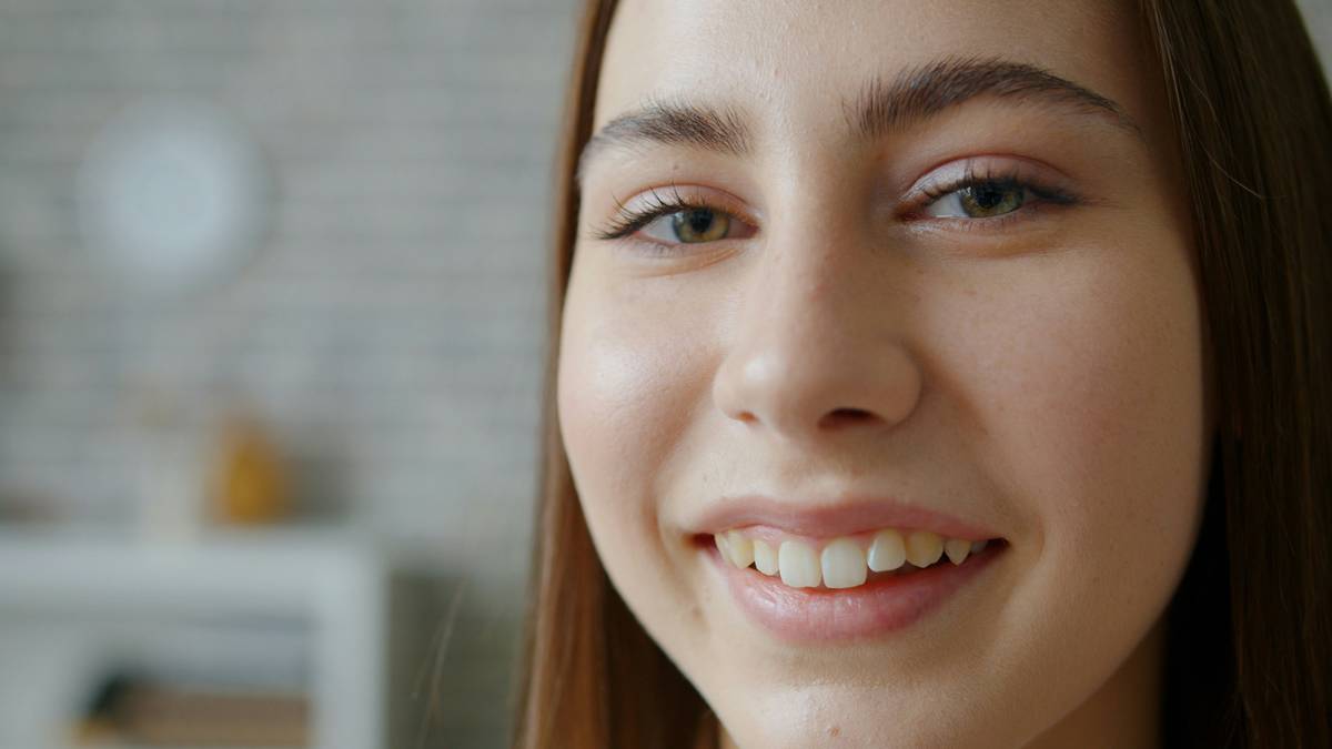 Teen applying dewy foundation for vibrant youthful look before prom