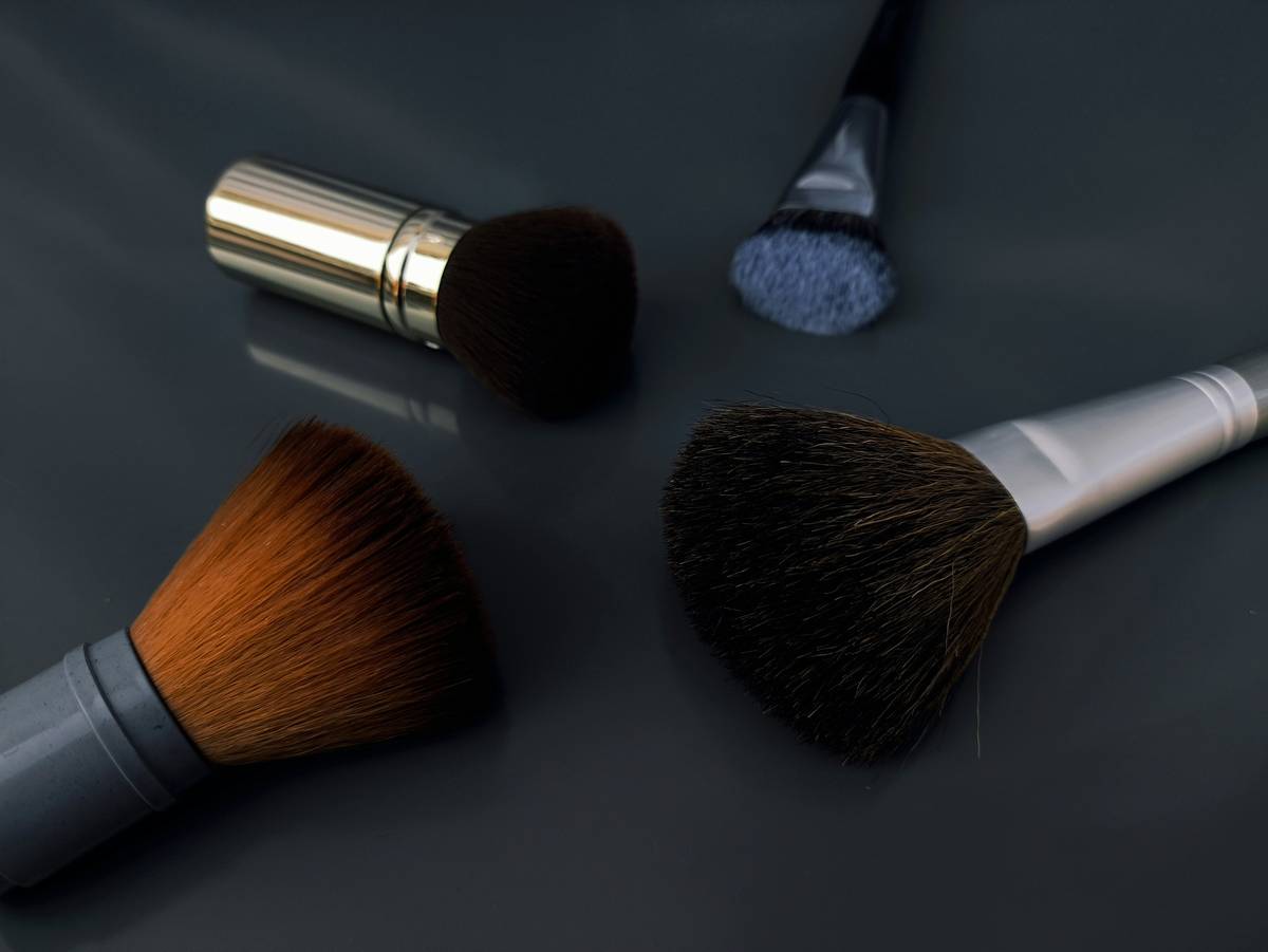 Close-up of a dancer applying stage makeup essentials including bold eyeliner, matte foundation, and setting powder
